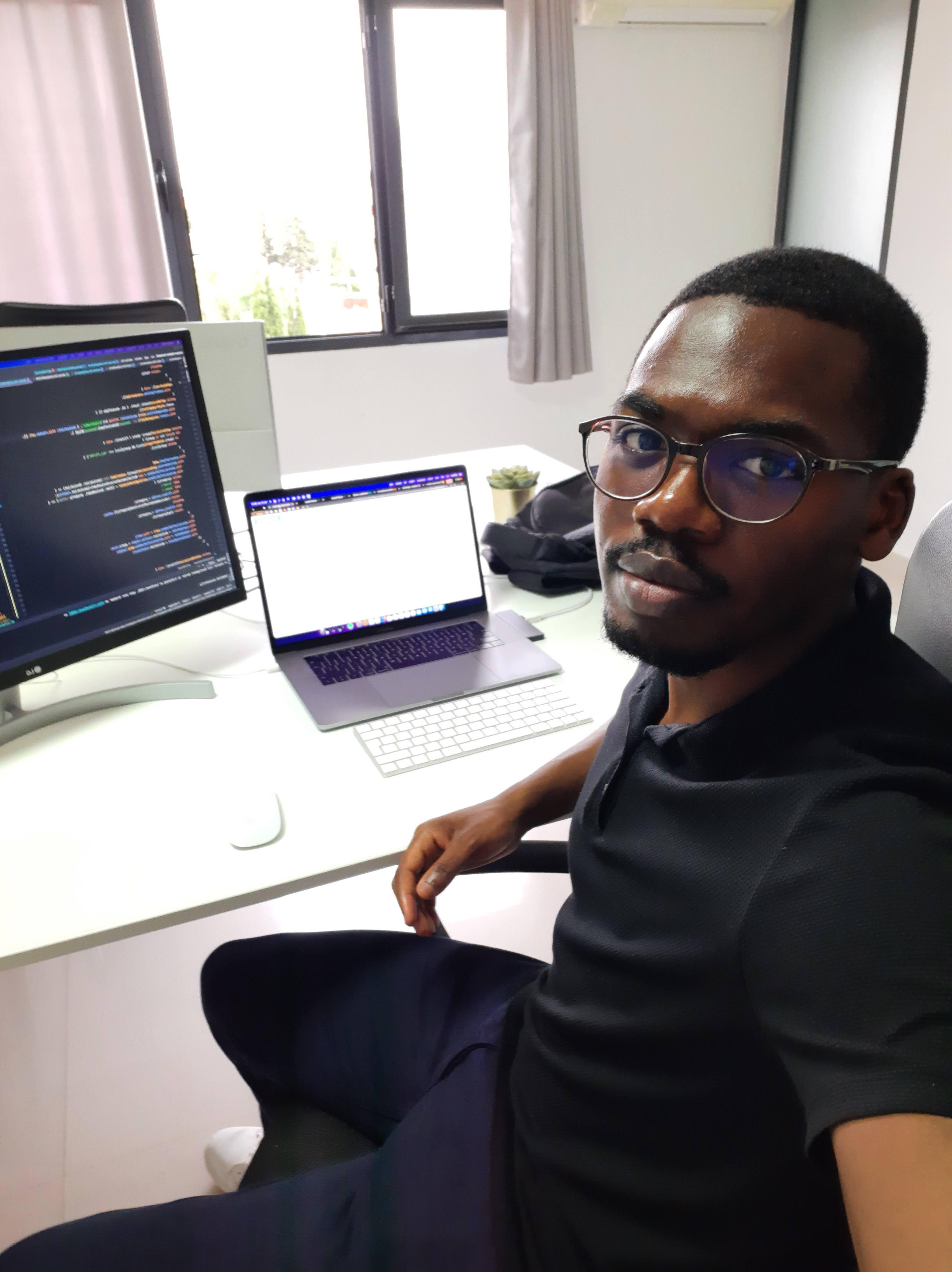 Kabuswe Mulenga at his desk, working with code on screen